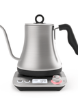 The Magic Hour Starter Kit by Magic Hour features a stainless steel electric kettle with a gooseneck spout that sits on a digital base—perfect for your tea ceremony. The base includes an LED display showing the temperature and various settings, with an adjustable knob and buttons for control. The kettle is designed with a black handle and has a lid equipped with a circular handle.