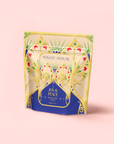 A vibrant tea pouch labeled "MAGIC HOUR" features "Pecan Pie Chai" on a rich blue panel, with yellow and pink floral designs suggesting warm chai spices and calming ashwagandha inside.