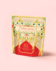 The "Peppermint Bark Puerh" pouch displays festive green, gold, and red patterns on a pale pink background—a perfect gift for anyone who loves the rich taste of dark chocolate peppermint tea.
