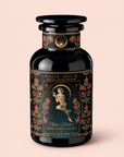 A black decorative tea jar labeled “Persephone’s Potion: Pomegranate & Jasmine Green Tea,” adorned with gold accents, floral illustrations, and an image of a winged woman holding a flower. This enchanting jar evokes the allure of pomegranate and jasmine green tea, inviting you to indulge in a magical blend both inside and out.