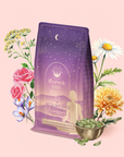 A purple bag of Pitta: Caffeine-Free Saffron Tea for Balancing Body, Mind & Emotions is displayed among vibrant flowers and a bowl of green cardamom pods on a soft pink background.