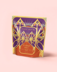 A colorful pouch labeled "MAGIC HOUR" with ornate orange, gold, and purple designs features "Pumpkin Spice Fireside Chai"—an antioxidant-rich, caffeine-free herbal tea—set against a light pink background.