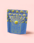 A blue and yellow resealable pouch labeled "Queen of Ukraine: Spring Blossom Tea," decorated with sunflowers and florals, is shown on a light pink background.