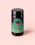 A black jar with a green label that reads “Renewal: Peach-Goji-Rose Oolong Tea, Net Weight 1oz (28g),” sits on a light pink background, evoking the delicate blend of oolong tea with fruity notes of goji berries and peach inside.
