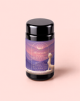 A black tea canister labeled “Restful Evening Chai: Dosha Balancing Saffron Spice Tea” features a purple and peach label with the silhouette of a seated person, highlights saffron and suitability for all body types against a soft pink background—ideal for those seeking an herbal chai experience or dosha balancing tea enhanced by the calming notes of saffron.