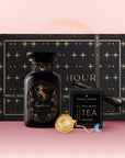 The Sagittarius Astrology Tea Gift Set includes a black “Magic Hour” gift box with gold stars, a black jar with a Sagittarius centaur, a tea infuser, and an “Opal Moon Ritual Tea Infuser,” all beautifully arranged on a pink background.