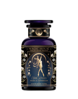 A dark blue apothecary jar labeled "Skadi The Sovereign" features a gold illustration of a woman with a bow and arrow amid floral designs, celebrating Skadi’s sovereignty with winter berry Pu-erh tea.