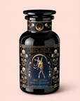 A black and gold canister labeled “Skadi The Sovereign: Winter Berry Puerh” displays an illustration of a woman with a bow, surrounded by floral designs, and text reading “The Rises.” With its berry-infused pu’erh blend, this tea is perfect for enjoying on chilly evenings and celebrates the resilience of winter. The background features a soft light pink hue.