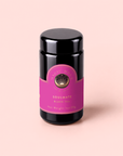 A black jar labeled “Soulmate: Chocolate-Raspberry-Rose Black Tea for Finding & Celebrating Love,” adorned with a pink and gold design, sits on a light pink background—a wellness-boosting tea inspired by rich notes of chocolate, raspberry, and rose.