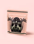 A stand-up pink pouch labeled "Summer Fridays" with palm trees and tigers contains Strawberry Daiquiri: Green Berry Mocktail Tea for Beautiful, Hydrated Skin from Within, set against a light pink background.