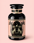 A black and pink bottle labeled “Strawberry Daiquiri: Green Berry Mocktail Tea for Beautiful, Hydrated Skin from Within,” featuring palm trees and a tropical design, is set against a light pink background—evoking the refreshing vibe of a green berry mocktail tea that’s perfect for those who love summer tea moments.