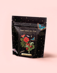 A black resealable pouch labeled “Strawberry Shortcake Iced Tea with Hibiscus” displays strawberries, hibiscus flowers, butterflies, and stars illustrations on a pale pink background.