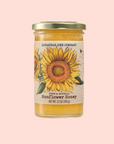 A 12 oz (340 g) jar of Savannah Bee Co. Honey - Sunflower, with vibrant sunflower illustrations, glows against a pink backdrop, showcasing the dedication of beekeepers.