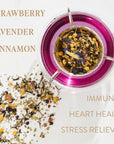 A top view of a glass teacup containing vibrant purple organic tea with various loose herbs. Surrounding the cup are scattered herbs. Text on the image lists ingredients and benefits: "Strawberry, Lavender, Cinnamon" and "Immunity, Heart Health, Stress Reliever." Discover Symbeeosis: Beautifying Immunitea for the Queen Bee by Magic Hour today.