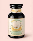 A dark glass jar labeled "Tea for Beauty: Renewal: Peach, Goji & Rose Oolong Tea," adorned with gold and pastel designs featuring celestial and floral elements against a light pink background. This enchanting blend shines with notes of peach, goji, and rose oolong tea, capturing elegance and renewal in every cup.