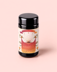 A black tea canister labeled “Tea for Energy: Bohemian Breakfast” from the brand Magic Hour, featuring a sunburst design, floral accents, and a light pink background, with an energizing probiotic-rich puerh black tea blend.