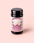 A canister of Tea for Peace: Child’s Pose—Citrus, Lavender & Tulsi Herbal Tea Blend—adorned with a purple, gold, and floral design, rests on a soft pink background. The label highlights citrus lavender notes, 8 plant silk tea sachets, and heart chakra themes—an adaptogenic blend carefully crafted to relax your nervous system and nurture inner calm.