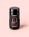 A black tea canister titled “The Lovers Hibiscus-Cinnamon-Vanilla Love Potion” features an illustrated label of two people embracing among pink roses, set against a light pink background. This special blend combines sensuality tea with women’s balancing herbs, inviting you to savor a moment of romance and connection with every cup.