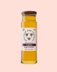The Savannah Bee Co. Honey - Tupelo is presented in a clear glass bottle with a brown lid and a beige label reading "Savannah Bee Company, Pure & Natural, Made in USA." The 12-ounce (340g) bottle is set against a peach-colored background.