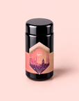 A black cylindrical jar with a pink and gold label adorned with geometric patterns and building silhouettes, set against a light pink background. Turkish Delight is a caffeine-free herbal tea inspired by the classic flavors of Turkish delight, bringing a taste of tradition to your cup.