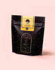 A black stand-up pouch labeled "Magic Hour" with gold stars and text displays Citrine Cleanse™ Herbal Tea, a caffeine-free detox blend, set against a pale pink background.