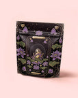 A black resealable bag with purple lotus and a mystical woman under a starry sky, labeled "The Moon - Tea for Nurturing Graceful Phases," hints at a calming herbal blend with butterfly pea flower, set on a pale pink background.