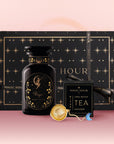 The Virgo Astrology Tea Gift Set features a black and gold tea canister, "Magic Hour" box, tea infuser, and wellness blend sachets, all beautifully arranged on a pink gradient background.