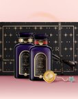 The Wake Up & Wind Down Tea Gift Set features two dark purple and gold “Magic Hour” tea jars, an elegant black gift box with gold starburst designs, a tea infuser, and a star-shaped charm on a pink surface.