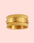 The Inner Light I Am Loved Spinning Ring, plated in 18KT gold with beaded edges, features "I AM LOVED" engraved on its smooth central band, symbolizing unconditional love against a white background.