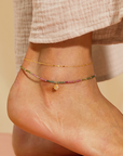 A close-up of a person's ankle wearing light textured pants and a 9" shimmering chain anklet with a 1" extender adds an elegant touch.