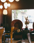 A lounge area at The Soul of Tea: A Two Day Retreat in Ojai, CA featuring wicker peacock chairs and a carved Thai-style figure standing on a side table.