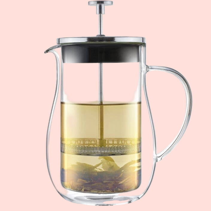The Teabloom Louvre Insulated Double-Walled Glass French Tea Press features a clear handle, metal lid and plunger, and showcases light tea with loose leaves at the bottom—all elegantly set against a clean white background.