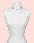 The Tourmaline Gold Moon Choker Necklace, featuring minimalist colorful beads, is displayed on a white dress form mannequin against a simple white background.