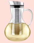 The Teabloom Multi-brew Glass Teapot + Kettle + Pitcher (51 oz) features a metal lid and handle, a stainless steel tea infuser, and is shown with light yellow liquid inside.