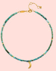 A delicate 9" turquoise moon anklet with small turquoise beads, gold accent beads, an adjustable gold clasp, a 1" extender chain, and a gold crescent moon charm—a timeless celestial accessory for any look.