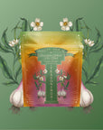 A decorative package labeled "Teasoning: Roasted Garlic Tea Salt" stands before a green background, artfully framed by illustrated garlic bulbs, oolong tea leaves, white flowers, and leafy accents on both sides.