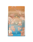 Magic Hour’s Thai Temple Tea Case Packs come in vibrant, colorful packaging adorned with East Asian elements like a dragon, a temple, cherry blossoms, and a Buddha statue. The package features a stunning blend of brown and gradient blue hues with intricate details and patterns. Each pack contains probiotic-rich Puerh tea and has a net weight of 4 oz (113g).