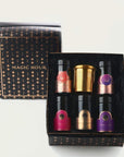 A black and gold gift box labeled "Blissful Black Teas Medley" from Magic Hour contains five small bottles with colored labels, each filled with organic loose leaf tea, and a single gold candle holder. The bottles are arranged in two rows, with two bottles and the holder on the top row and three bottles on the bottom row.