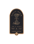 A label for "Magic Hour Almond Matcha Green Tea." The design features an hourglass adorned with stars and moons in a vintage style, and the text reads "Time for Infinity," "Ceremonial Teas," and "Made with Love" on a black background highlighted with gold accents. This standalone gold foil front jar label, named Magic Hour Front Jar Label, reincarnates timeless elegance.