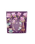 A purple tea package adorned with an illustration of pink flowers, teacups, a teapot, and the Eiffel Tower evokes a romantic interlude. The standout design features a diamond-shaped emblem with celestial symbols and the text "Breakfast in Paris - Oolong Black Tea Scented with Fruits & Flowers of Secret Parisian Gardens.