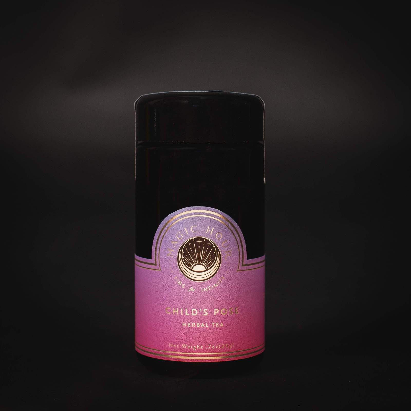 A cylindrical, black metal container of Magic Hour Drift into Sleep Ritual Gift against a dark background. The label at the bottom features a gradient from deep pink to light pink, with gold lettering and a circular logo in the center.