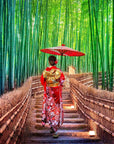 A person wearing a traditional red and gold kimono and holding a red umbrella walks along a pathway lined with bamboo on both sides. The scene is vibrant and serene, much like the calming experience of enjoying Kansai-Kyoto Ceremonial Matcha by Magic Hour, with lush green bamboo towering above.