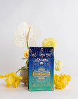 A vibrant card with the text "Mercury Mint Nighttime" is displayed against a pristine white background. It is surrounded by bright yellow and white flowers in a minimalist vase, enhanced by the soothing presence of lavender, adding a touch of natural beauty to the scene.