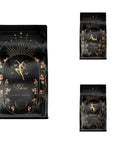A black, starry, Libra-themed coffee package adorned with gold celestial graphics and pink floral accents. The main bag showcases a centered illustration of a woman holding scales. Two smaller packages featuring the same design accompany the main bag on the right side, making it perfect for pairing with your favorite Libra tea from the Astrology Bundle: Libra, Scorpio, Sagittarius collection.