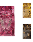 Three coffee bags are displayed against a white background. The largest bag on the left features a pink geometric design with a heart outline, reminiscent of the "Pink Tourmaline" in the Gemstone Bundle. The two smaller bags on the right have yellow and black geometric designs with a similar diamond pattern, capturing the essence of unique blends in "Topaz & Onyx.