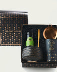 Ceremonial Matcha Traveler Gift Box with a "Magic Hour" theme. Includes a tin of loose leaf tea, green tea bottle, golden tea spoon, black tea bowl with metallic dots, and copper tea strainer. Set is displayed in a black box with a starry pattern.
