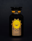 A black glass bottle with a wide black lid, labeled "Salutation™ Tea for the Solar Plexus Chakra" in a golden circle design featuring the solar plexus chakra symbol. The label states: "Solar Plexus Chakra Tea Blend," "Salutation," and "Ceremonial," on a dark background, perfect for achieving chakra balance with organic ingredients.