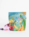 A vibrant packet of Tulum Horchata Chai Case Packs by Magic Hour, adorned with colorful illustrations of birds, flowers, and tropical foliage. The packet stands against a white background with fresh blooms artistically arranged at its base.
