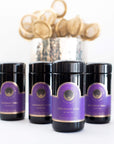 The image shows three black cylindrical containers labeled "Blissful Black Teas Medley" with purple and gold labels from "Magic Hour" placed on a white surface. Behind them, a reflective silver container holds numerous tea strainers or infusers, hinting at the exquisite loose leaf tea experience within.