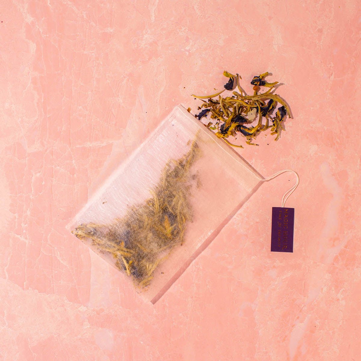 Arranged tea set with bottle, flowers, and decorative items on a satin cloth.